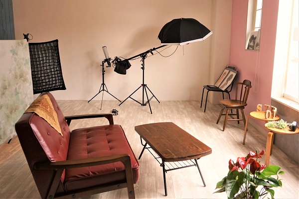 室内にテーブル、傘、ソファがあるスタジオ